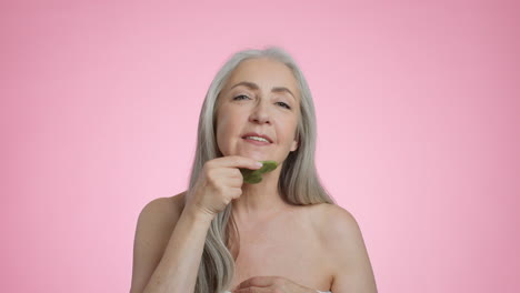 senior woman practices skincare with gua sha tool for anti-aging benefits