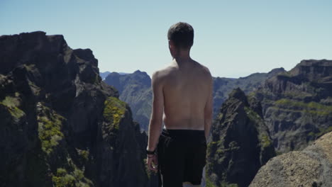 young man stands in beautiful mountains of madeira portugal, slow motion