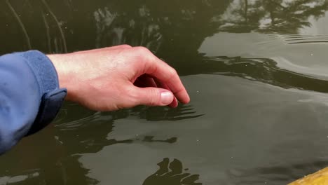 a man puts fingers down in lake kayaking