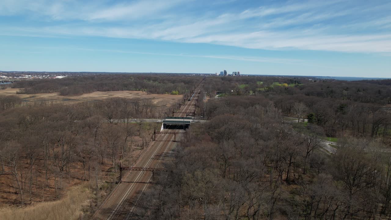una vista aérea de un tren que se acerca, viajando hacia el puente ferroviario de pelham bay en el bronx, nueva york en una mañana soleada