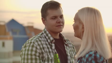 una pareja amorosa con camisas a cuadros disfruta de un momento juntos en el techo. los hombres miran a los ojos a su novia.