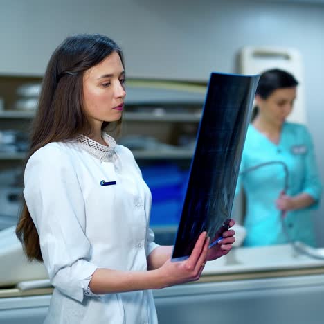 young medical doctor with an x-ray. beautiful female expert examining radiograph picture of a patient in the modern medical room in clinic.