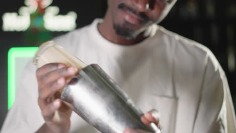 bartender focusing while shaking cocktail shaker, hands gripping tightly in motion. blurred bar background with bottles, highlighting drink-making skill and bartender performance in action