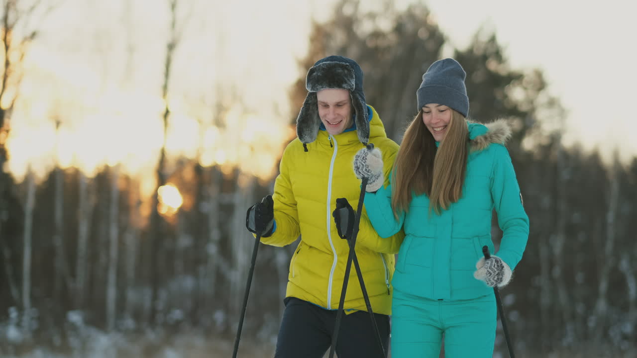 Full length portrait of active young couple enjoying skiing in snowy winter forest, focus on smiling woman in front, copy space