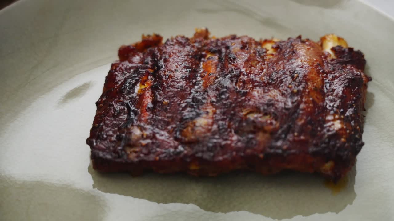 Crop person putting fried ribs on plate