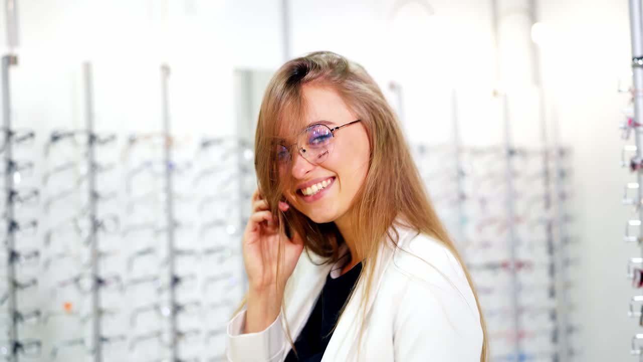 Young woman checking her new glasses at optics. Beautiful smiling girl wearing glasses and posing on camera.