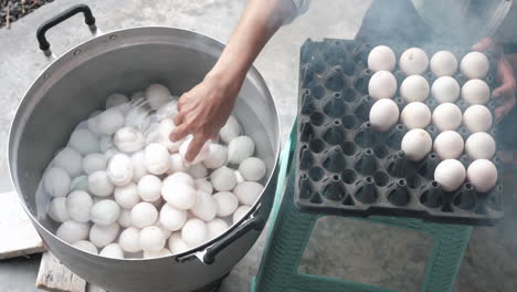 top down shot eggs being added to a pan of hot water - duck eggs thai dish