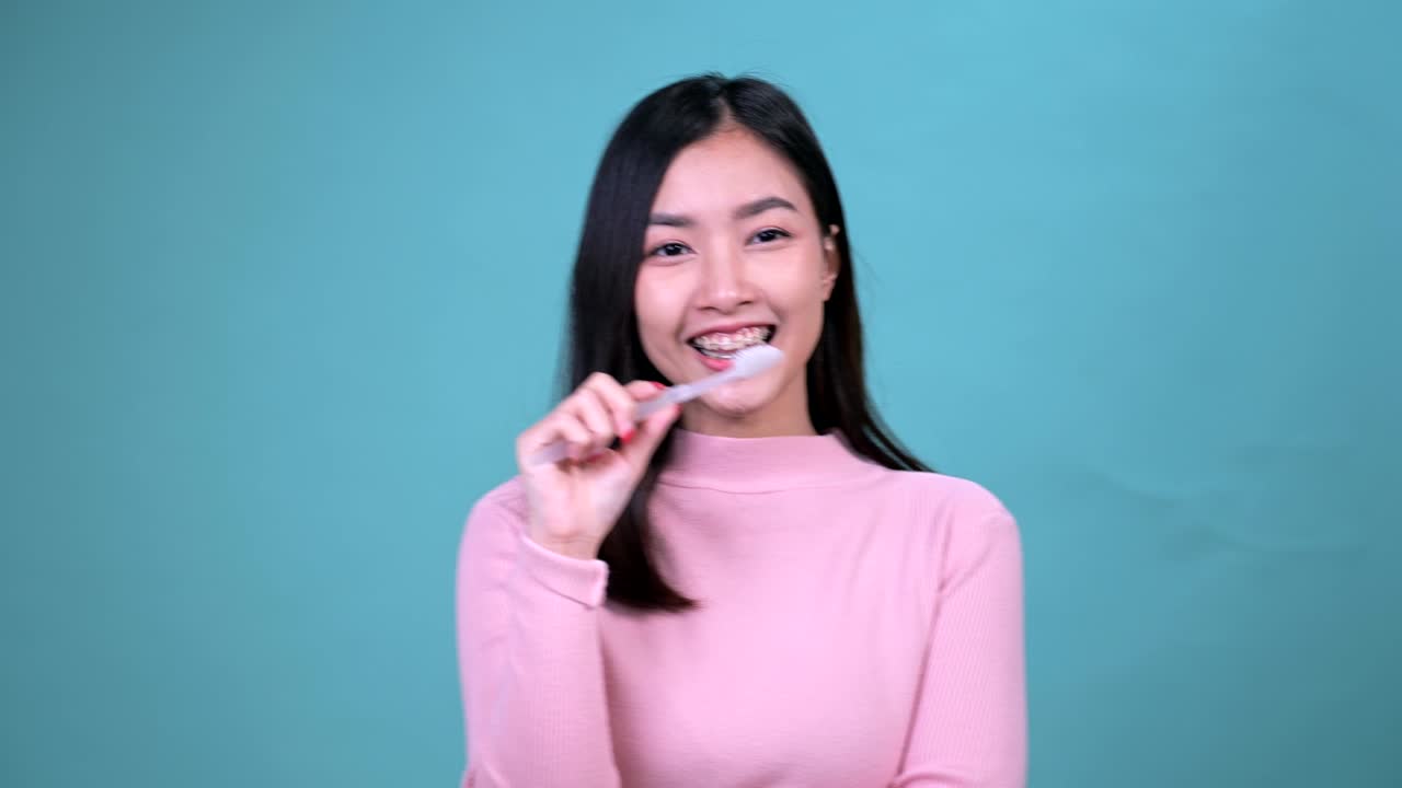 푸른 스크린 배경에 정형 치과 장치를 착용 한 미소 짓는 아시아 여성. 치과 관리와 건강한 치아.