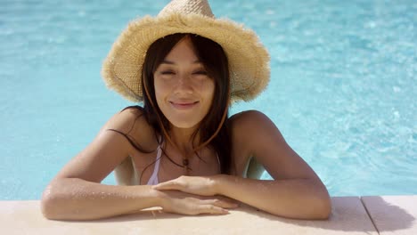 Woman-in-straw-hat-and-swim-suit-stands-in-pool