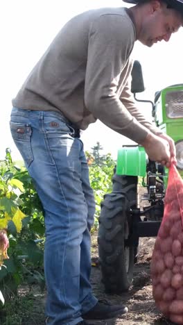 a farmer carries a heavy sack of fresh potatoes through a green field while a bright tractor stands a farmer carries a heavy sack of fresh potatoes through a green field while a bright tractor stands nearby