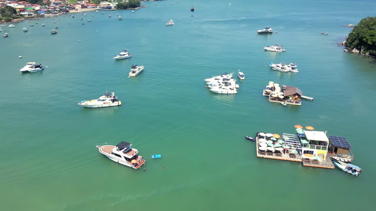 Boats And Yachts With Floating Bars On Vibrant Blue Water Of Porto Belo In Santa Catarina, Brazil. aerial shot