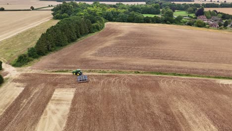 aerial static overview of a tractor working as it turns on the harvested fields in etchilhampton, uk, with visible crop lines