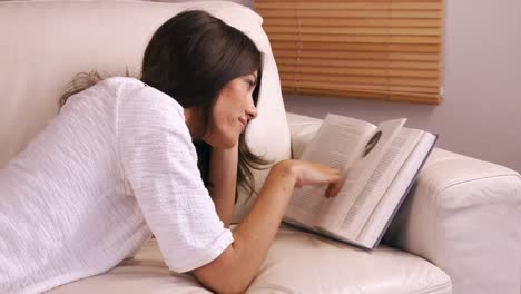 Smiling-woman-reading-a-book-on-sofa