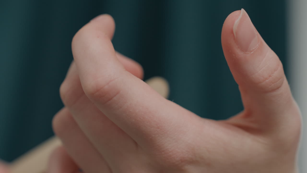 Closeup hands holding wooden stick during cuticle push, professional salon backdrop, steady grip and precise thumb motion, soft teal curtain, hygienic technique and soothing grooming ritual, focused