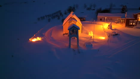 orange lit church in a thick pack of snow in iceland at night