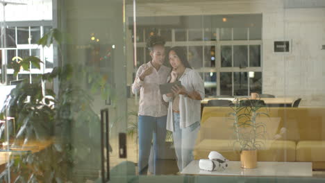 Young-African-American-woman-and-biracial-woman-discuss-over-a-tablet-in-a-business-office-setting