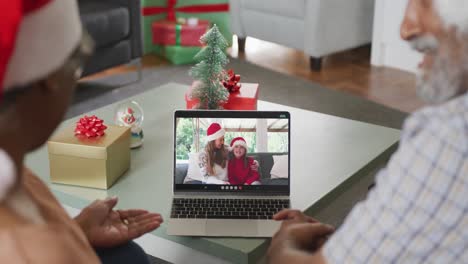 Happy-african-american-senior-couple-on-video-call-with-female-friend-and-her-daughter-at-christmas