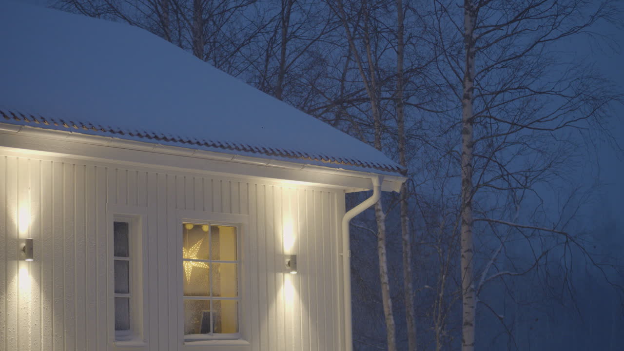 Julbelysning lyser genom fönstret en snöig, tyst kväll.
