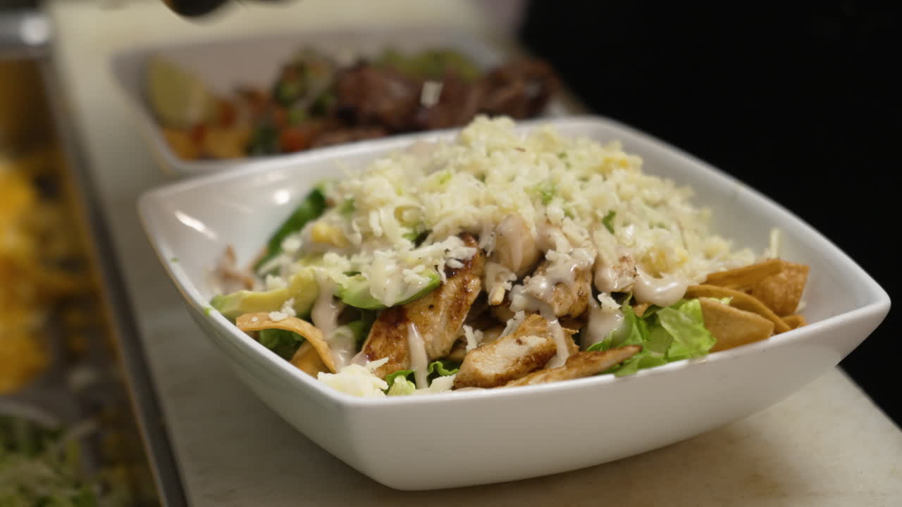 cocinar la ensalada de fajita de pollo con queso triturado, mano con guante rocía queso para terminar la ensalada, cerrar la cámara lenta 4k