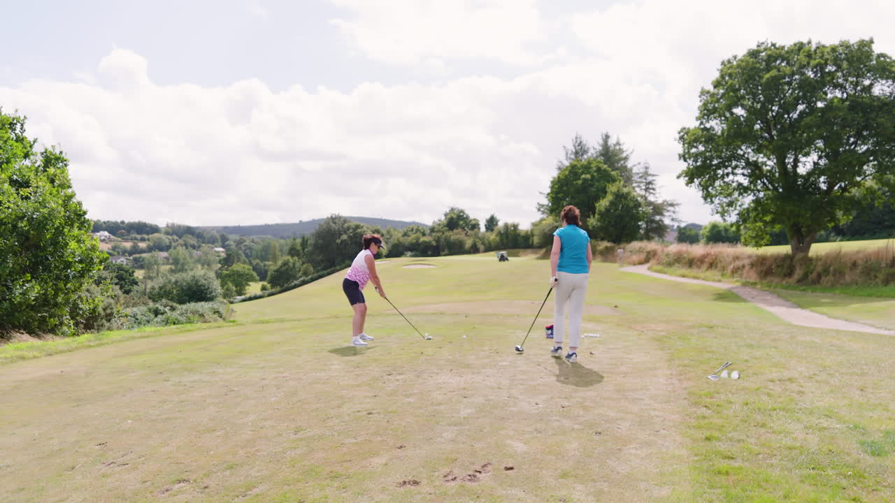 Female golf players playing golf and knocking golf ball out on golf course, copy space
