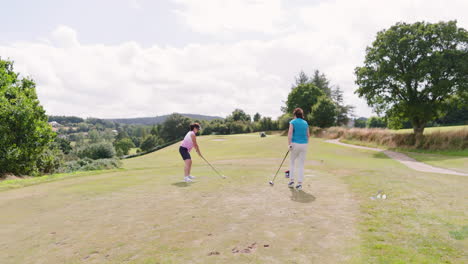 female golf players playing golf and knocking golf ball out on golf course, copy space