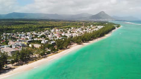 tramo de arena blanca salpicada de árboles y grupos de edificios en la playa de flic en flac