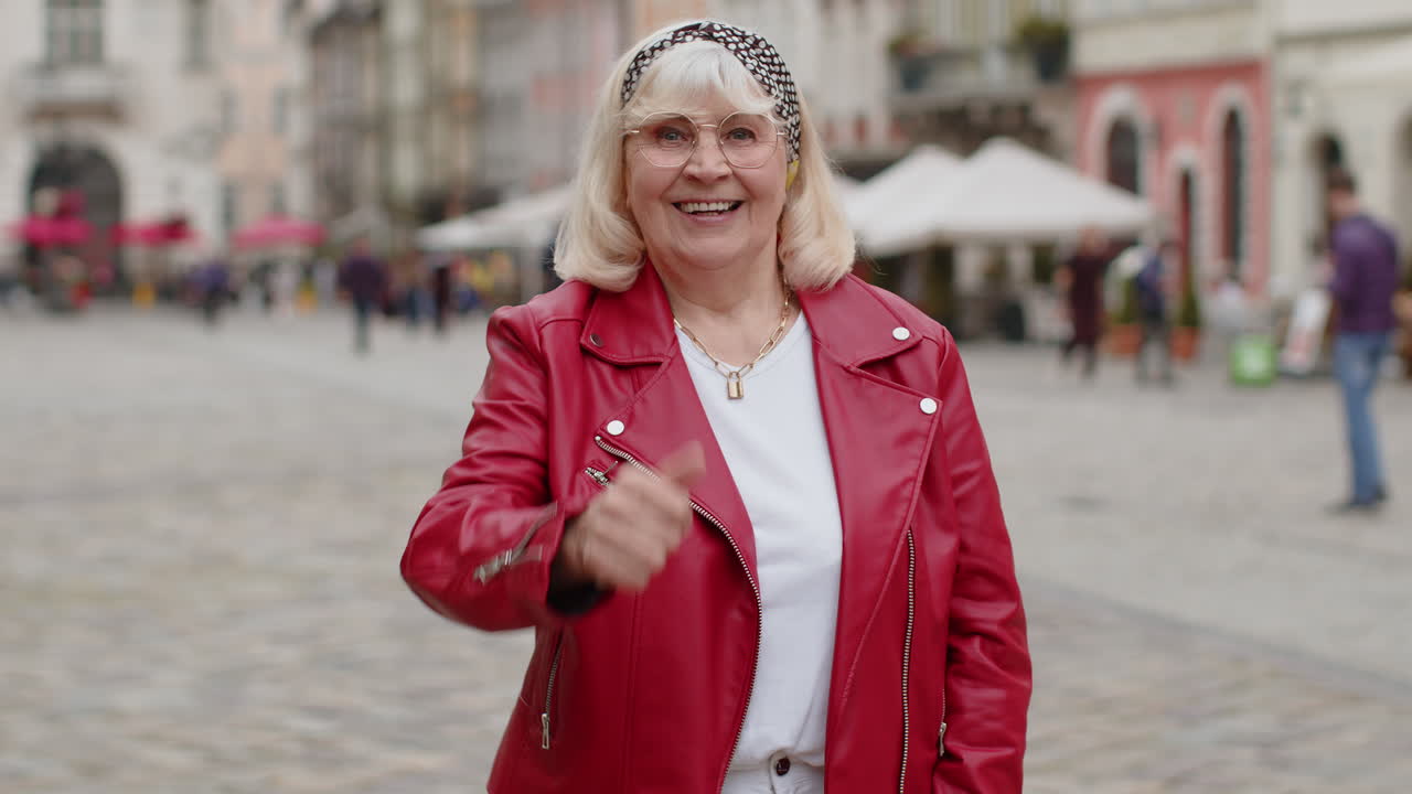 Senior woman showing thumbs up like sign positive something good positive feedback in city street