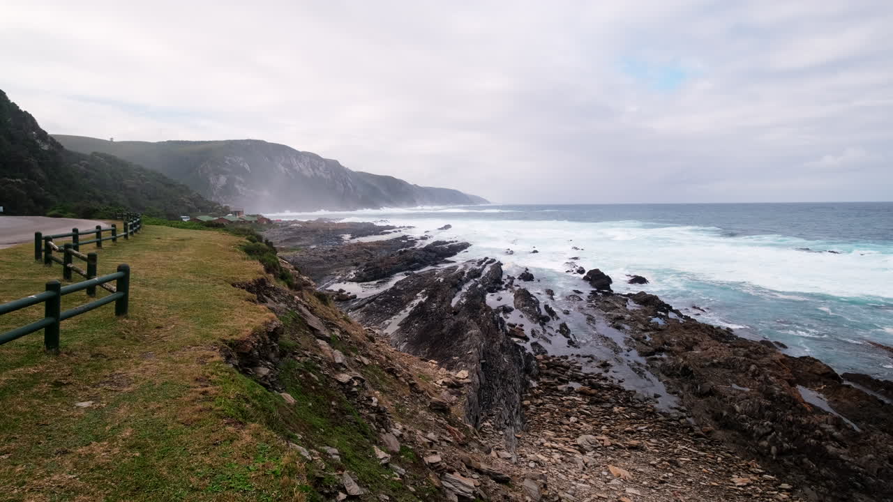 Foaming waves crash onto rocky shoreline of Storms River Rest Camp, Tsitsikamma