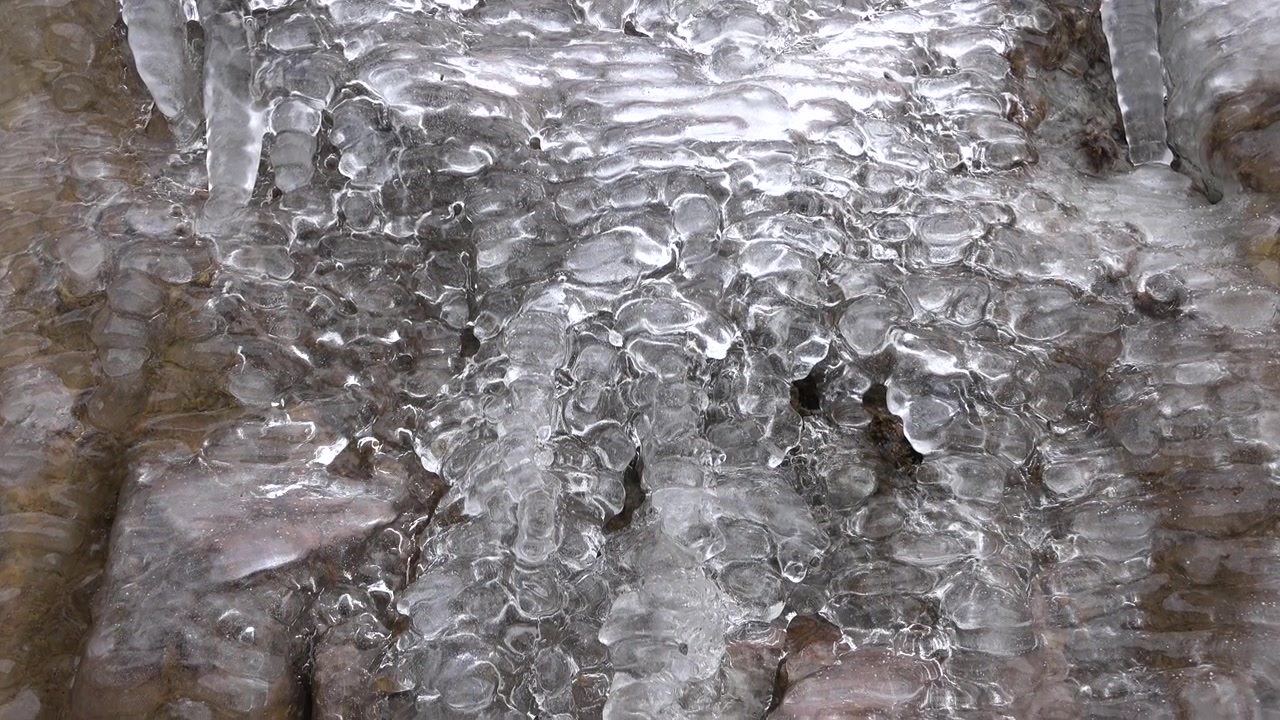 Acqua che scorre su rocce ghiacciate in inverno.