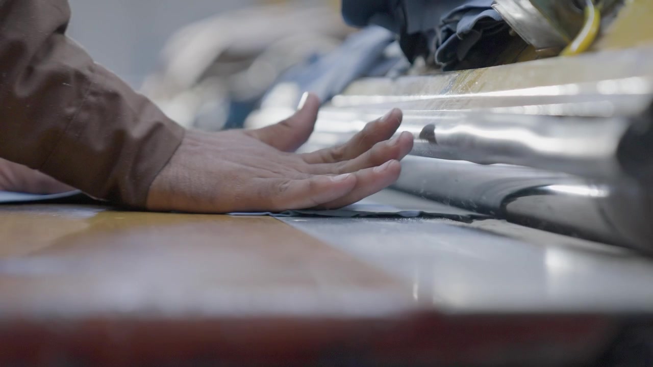 Machine Operator Feeding Leather Hides Into A Production Machine In A Industrial Manufacturing Factory.