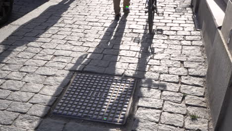 Close-up-of-cyclist-walking-with-his-bike-on-the-street-sidewalk-paving-slabs