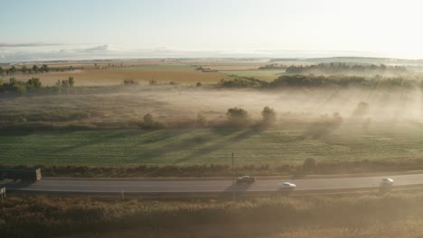 low morning fog shrouds the landscape and creates driving hazard for traffic on highway