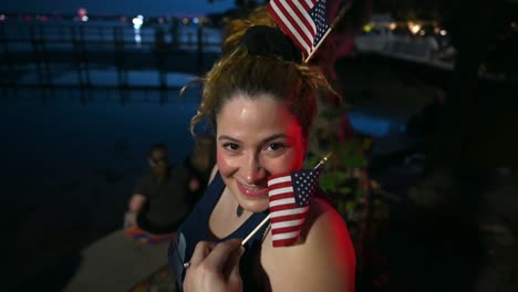 woman posing for picture with american flags at night