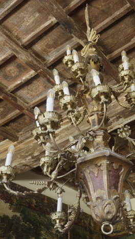 ornate golden chandelier hanging from a wooden ceiling