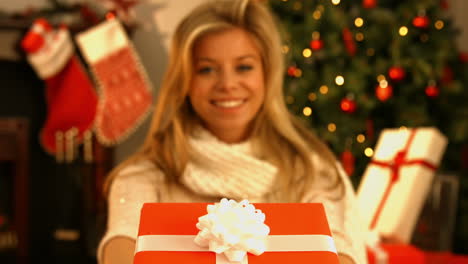 una rubia muy bonita mostrando un regalo.