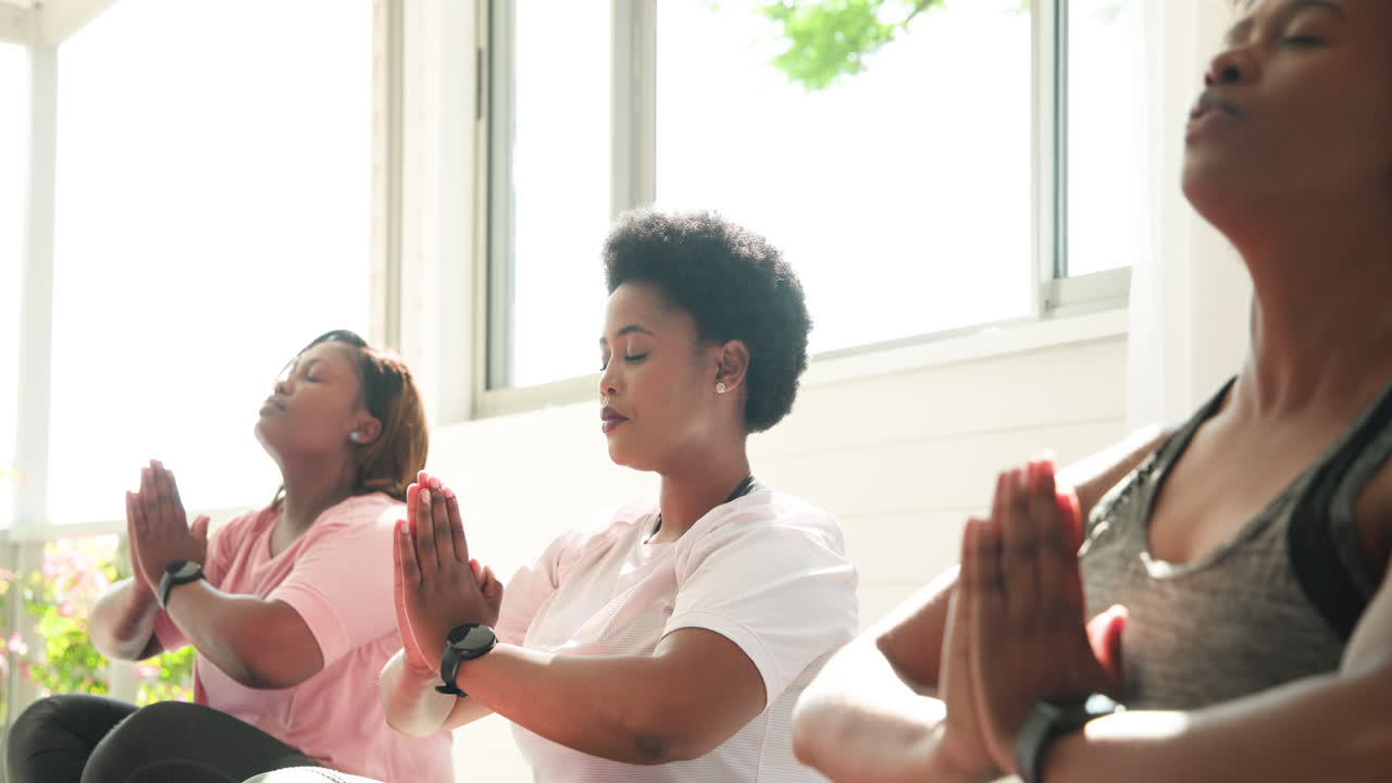 Smiling together, African American women practicing yoga in peaceful moment