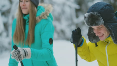 Loving-guy-and-girl-skiing-in-winter-forest-in-slow-motion-smiling-and-looking-at-each-other