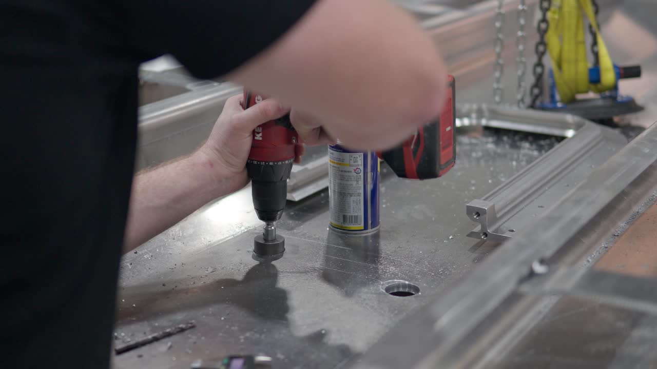 primer plano de las manos del hombre cortando el agujero en la hoja de aluminio usando la herramienta de corte de la broca de la sierra perforadora de acero del diente de la sierra para metal