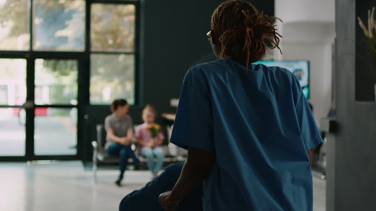 Assistente che aiuta un adulto in sedia a rotelle a incontrare la famiglia nella hall dell'ospedale