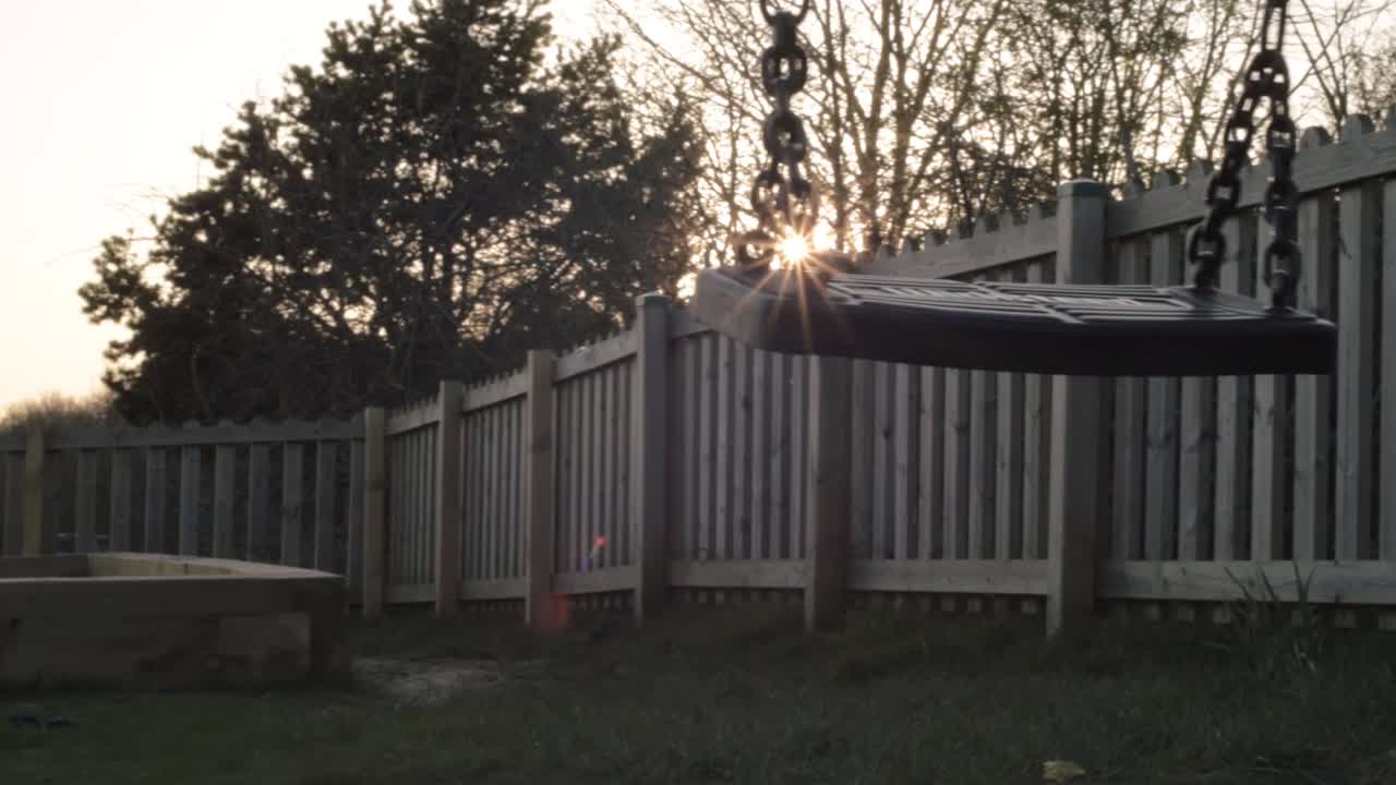 Cortile con staccionata in legno e altalena al tramonto