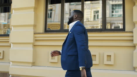 Young-businessman-running-in-hurry.-Afro-guy-walking-fast-at-urban-street.