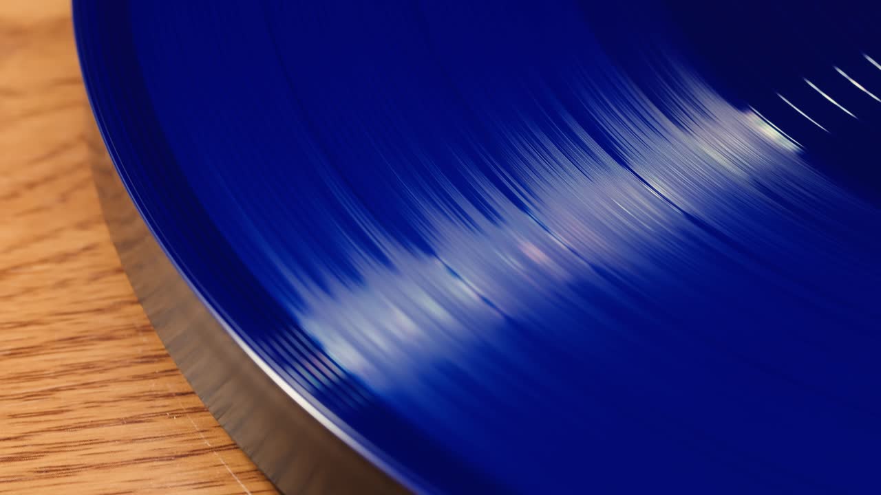 Primo piano di un disco in vinile blu che gira su una superficie in legno