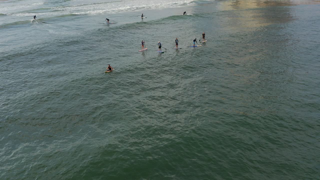 바다의 파도에서 서서 패들보더를 타는 사람들