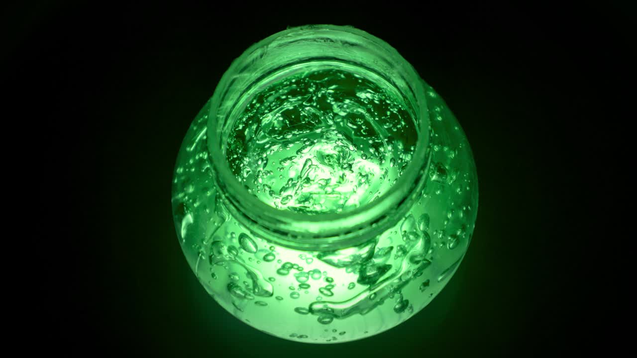 Aloe Vera Gel rotating and illuminating in a container with black background