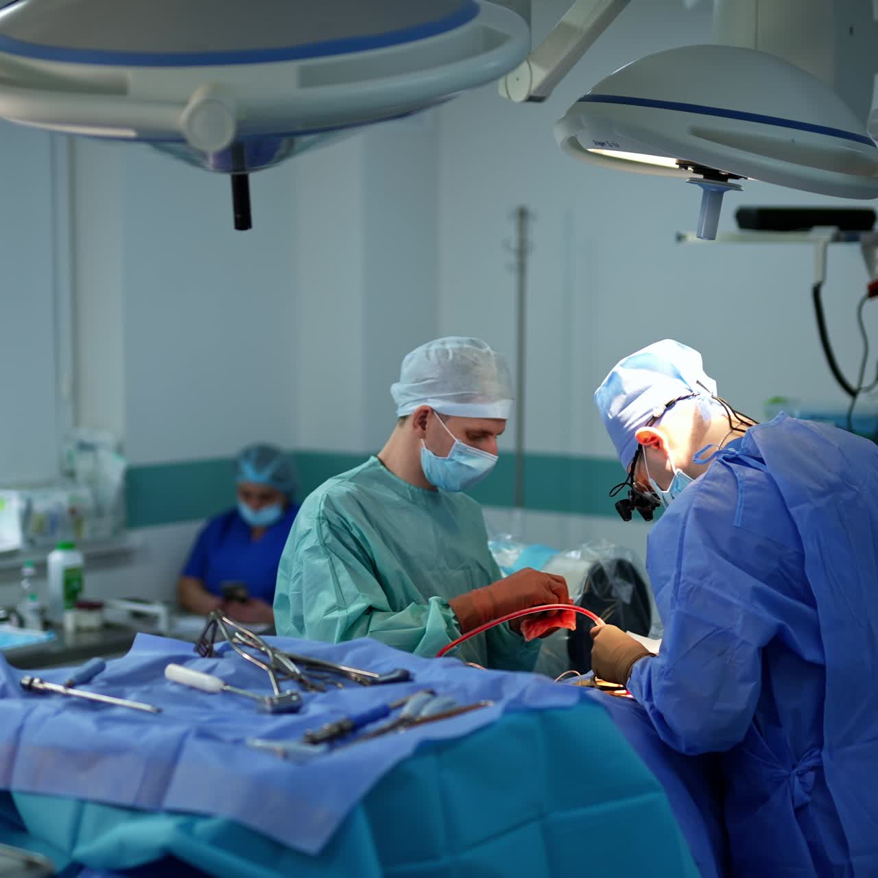 Surgeon helped by the assistant holds an instrument with tube full of blood. Medical staff workers at backdrop