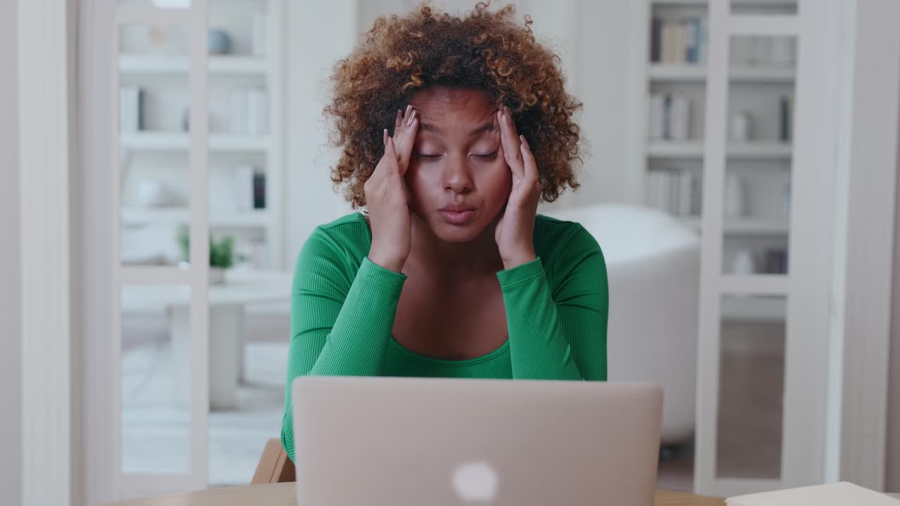 Young tired african american woman freelancer suffering from migraines