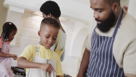 Glückliches-Afroamerikanisches-Paar-Mit-Sohn-Und-Tochter-In-Schürzen,-Die-In-Der-Küche-Essen-Zubereiten,-Zeitlupe