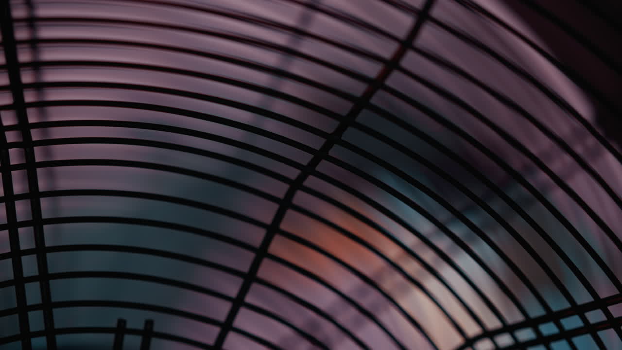 A close-up view of a black electric fan with its blades turning against a blurred background. The focus on the fan's grille and the motion of the blades