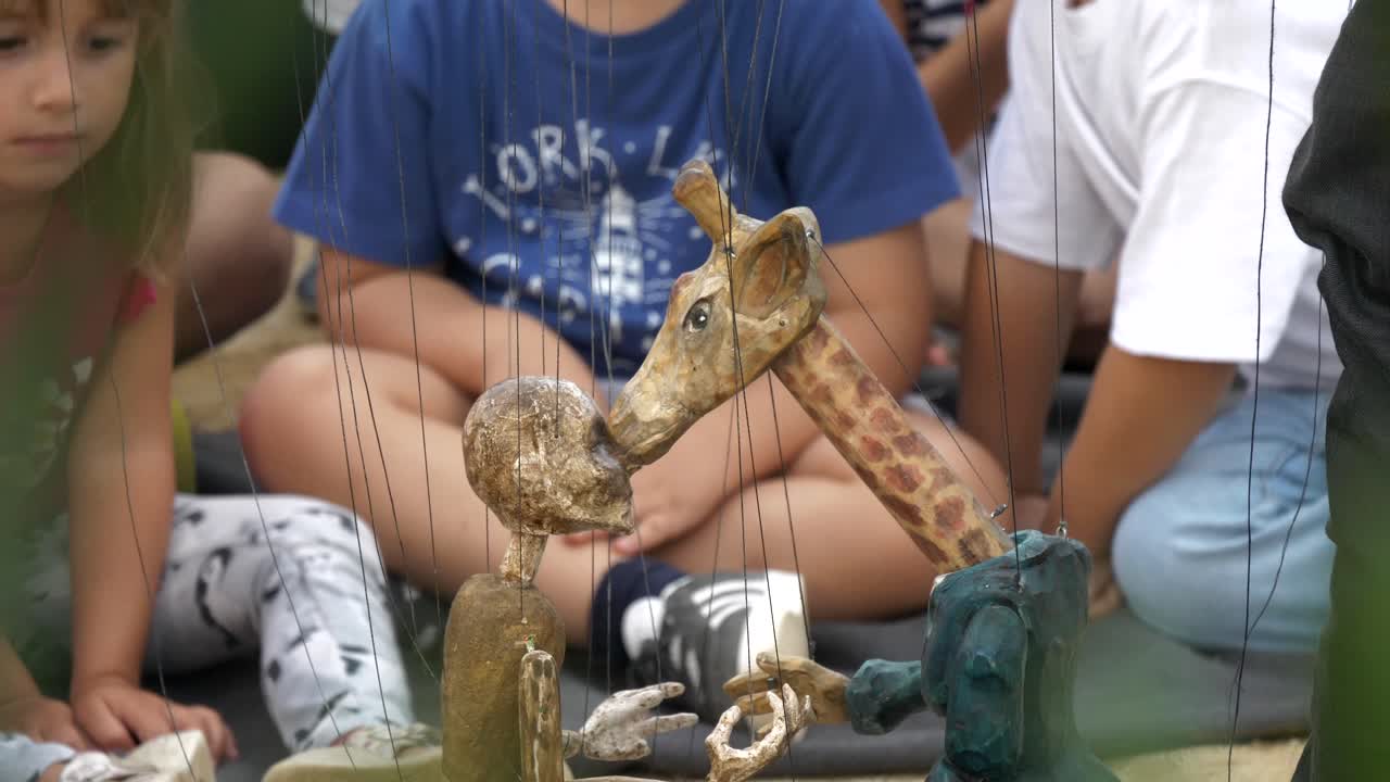 Kids watch giraffe and man marionettes at La Merce festival, Barcelona, Spain