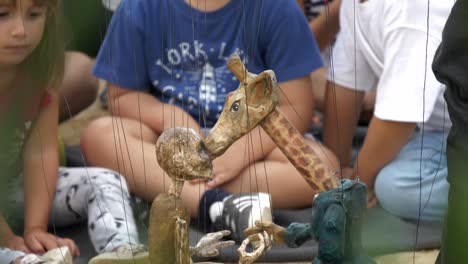 kids watch giraffe and man marionettes at la merce festival, barcelona, spain
